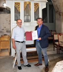 Pfarrer Michael Seils (l.) und Oberbürgermeister Bert Knoblauch mit der Urkunde des Romanikpreises 2021. © Stadt Schönebeck MichaelSeilsOB