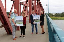 Hans Weber (Union Schönebeck), Karin Stagge (Stadt Schönebeck), Bert Knoblauch (Oberbürgermeister) und Julia Teige (Stadtwerke Schönebeck) präsentieren an der Ernst-Thälmann-Brücke das Plakat für den 8. Drei-Brücken-Lauf. © Stadt Schönebeck DreiBrückenLauf