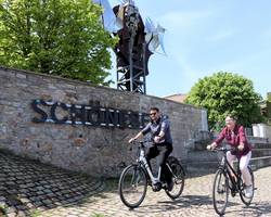 Stadtradeln geht in die nächste Runde. © Stadt Schönebeck (Elbe) Zwei Radelnde fahren vor dem Schriftzug Schönebeck und der Salzblume entlang.