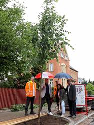 Baumpflanzung im Regen (v.v.l.): Thomas Iden, Geschäftsführer Planungsbüro igt Ingenieurgemeinschaft Thiel GmbH, Oberbürgermeister Bert Knoblauch, Sascha Jacob, Polier von ITB GmbH, Ines Scheffler, Mitarbeiterin Sachgebiet Tiefbau, und Dezernent Guido Schmidt. © Stadt Schönebeck (Elbe) Fünf Menschen sind beim symbolischen Einpflanzen einer Winterlinde aktiv.