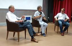 Drei Männer sitzen auf Sesseln vor einer Leinwand und sprechen über die Entstehung von EU und UNO.