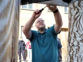Stadtrat Matthias Menzel befestigt das Schild an seinem Baum.