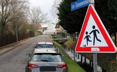 Zwei Autos stehen auf einer Schotterstraße neben einem Wassergraben.