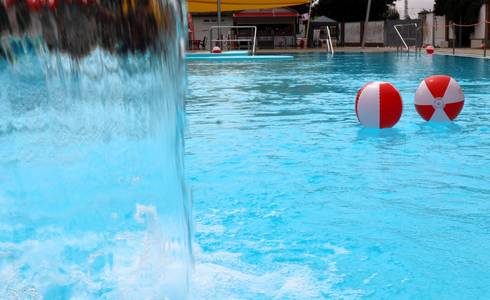 Wasserbälle schwimmen im Nichtschwimmerbecken vor einer Regendusche.