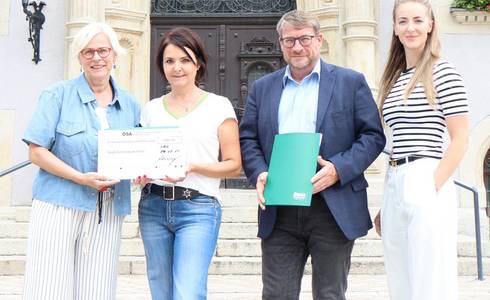 Eim Mann und drei Frauen stehen vor dem Schönebecker Rathaus und halten einen symbolischen Spendenscheck.